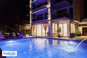a swimming pool in front of a building at night at Hotel Velkom in Sutomore