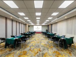 een conferentieruimte met groene tafels en stoelen en een scherm bij Jinjiang Metropolo Hotel Shenyang Country Garden Datong Lake Subway Station Branch in Shenyang
