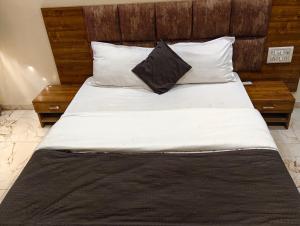 una cama grande con sábanas y almohadas blancas en Hotel Signature, en Ahmedabad