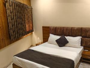 Un dormitorio con una cama con cabecero de madera. en Hotel Signature, en Ahmedabad