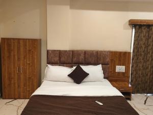 Un dormitorio con una cama grande con cabecero de madera. en Hotel Signature, en Ahmedabad