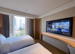 a hotel room with a large tv and a bed at JI Hotel Shanghai Baoyang Road Subway Station in Baoshan