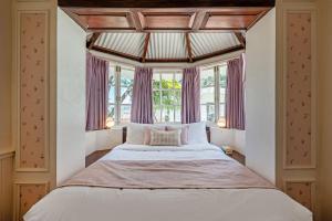 ein Schlafzimmer mit einem großen Bett mit einem großen Fenster in der Unterkunft Tiverton Bungalow in Udagamandalam