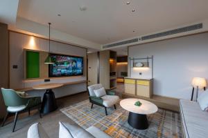 een woonkamer met een bank en een tv bij Holiday Inn Pu'er Jingmai by IHG in Mengman