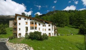a large white building on a hill in a field at Chesa Aquileja Trüb in Pontresina