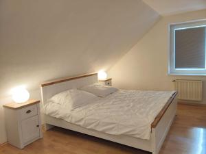 a bedroom with a white bed and two lamps at Ferienhaus Pfauenblick in Aurich