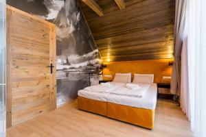 een slaapkamer met een bed en een houten wand bij Prywatna Sauna i jacuzzi! Tatra Spa Witów in Witów