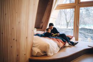 a man and a child sitting on a bed next to a window at SANU 2nd Home 山中湖1st in Yamanakako