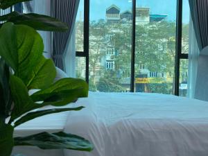 a bedroom with a white bed and a large window at Grand C Homestay in Hanoi