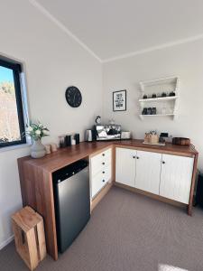 a kitchen with white cabinets and a wooden counter top at Cariad Apartment in Alexandra