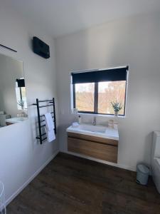 a white bathroom with a sink and a window at Cariad Apartment in Alexandra