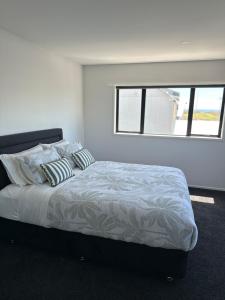 a bedroom with a bed with pillows and a window at Modern Costal Escape-with Spa in Papamoa