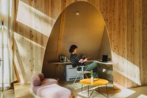 a woman sitting at a desk in a room with an archway at SANU 2nd Home 八ヶ岳2nd in Hokuto +59 photos
