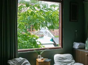 a bedroom window with a view of a tree at 25rooms Phan Thiet in Ấp Bình Hưng