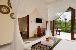 een slaapkamer met een bed met witte gordijnen bij Orchid Ubud Cottage in Ubud