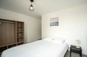 シャロン・シュル・ソーヌにあるLogement proche gare SNCFの白いベッドとナイトスタンドのある寝室