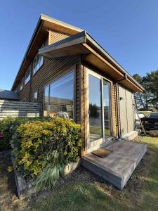 a tiny house with a wooden porch and glass doors at Whispering Pines in Kaihinu
