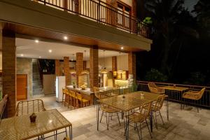 een patio met tafels en stoelen en een balkon bij Orchid Ubud Cottage in Ubud