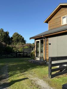 a wooden house with a porch and a fence at Whispering Pines in Kaihinu