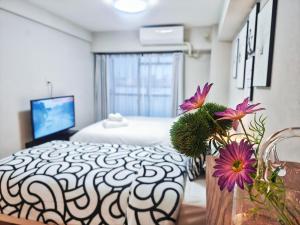 a bedroom with a bed and flowers on a table at Sidihome 365 Apartment in Osaka