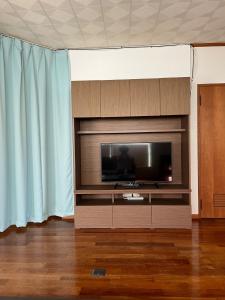 a flat screen tv in a living room with blue curtains at Mori no hoshi - Vacation STAY 65135v in Kunigami +16 photos