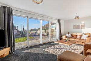 ein Wohnzimmer mit Couch und großem Fenster in der Unterkunft Swn Y Don - Modern Luxury Steps from Newgale Beach Bliss for up to 10 People in Newgale