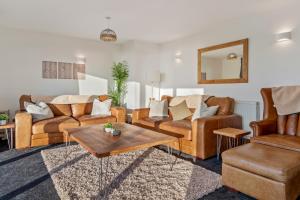 ein Wohnzimmer mit Ledermöbeln und einem Tisch in der Unterkunft Swn Y Don - Modern Luxury Steps from Newgale Beach Bliss for up to 10 People in Newgale