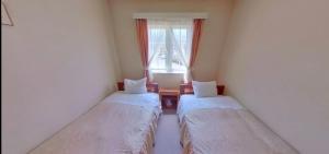 zwei Betten in einem Zimmer mit Fenster in der Unterkunft みんなの別荘ファミリア会津高原 in Minamiaizu