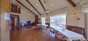 ein Esszimmer mit Tischen und Stühlen und einem großen Fenster in der Unterkunft みんなの別荘ファミリア会津高原 in Minamiaizu