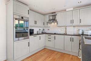 eine weiße Küche mit weißen Schränken und Holzböden in der Unterkunft Swn Y Don - Modern Luxury Steps from Newgale Beach Bliss for up to 10 People in Newgale + 32 Fotos