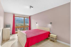 a bedroom with a red bed and a large window at Appartement T3 in Embrun