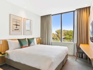 a hotel room with a large bed and a large window at Mantra on Sydney Airport in Sydney