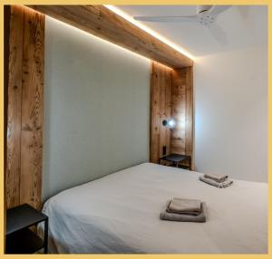 una camera da letto con un letto bianco con due asciugamani sopra di L'Élégance Alpine I Centre Les Gets a Les Gets