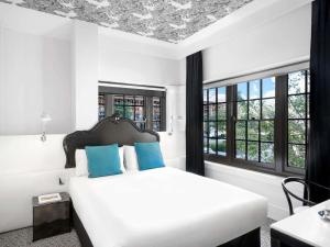 a bedroom with a white bed with blue pillows at Peppers Gallery Hotel in Canberra