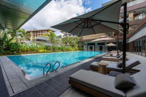 a swimming pool with lounge chairs and an umbrella at Holiday Inn Pu'er Jingmai by IHG in Mengman