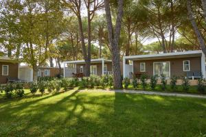 a house with a yard with trees and green grass at Costa D'Argento - Camping Village Club Capalbio in Capalbio