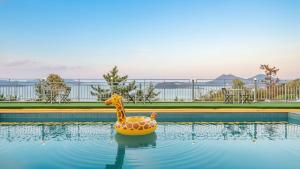 une girafe en peluche dans une piscine dans l'établissement Yeosu dasi bom pension, à Yeosu