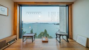 Cette chambre dispose d'une grande fenêtre offrant une vue sur l'eau. dans l'établissement Yeosu dasi bom pension, à Yeosu
