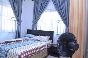 a bedroom with a bed with a fan and windows at Metroluxe in Akure