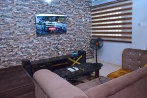 a living room with a couch and a tv on a brick wall at Metroluxe in Akure