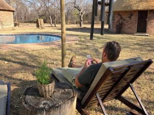 a man sitting in a chair in front of a pool at LoWes Africa in The Waterberg Biosphere