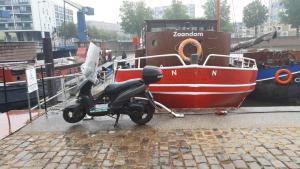 a motor scooter parked next to a red boat at Boat Hotel SIX Rotterdam in Rotterdam