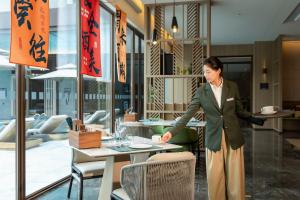 a woman standing in front of a table in a restaurant at Holiday Inn Pu'er Jingmai by IHG in Mengman +22 photos