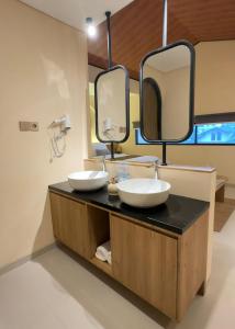 two sinks in a bathroom with two mirrors at Andara Villa Yogyakarta in Yogyakarta