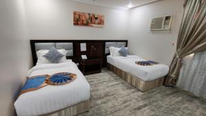 a hotel room with two beds with white sheets at الفرسان المتحده للشقق المخدومه الفيصليه ALFURSAN ALMOTAHIDA ALFAISALIA dist in Jeddah +79 photos