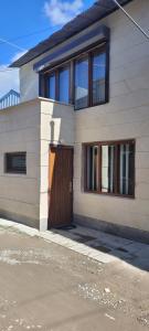 a white house with a wooden door and windows at Old Friends Guesthouse in Gyumri