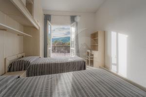 two beds in a room with a large window at Silvia sul Lungomare di Campo in Marina di Campo