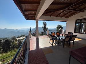 Un balcón de una casa con una mesa y sillas. en Hotel Goludev Valley View, en Nainital