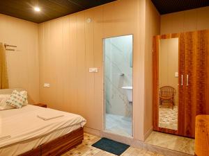 Un dormitorio con una puerta de cristal que conduce a un baño. en Karwaan by the Ganges, en Rishīkesh 75 fotos más