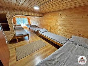 een kamer met 3 bedden in een houten hut bij Bucsin menedékház in Bucin